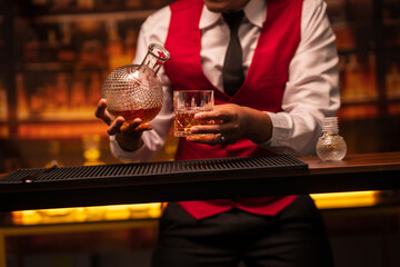 Business man bartender pours whiskey into a glass, sitting sadly in a restaurant	