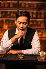 Business man bartender pours whiskey into a glass, sitting sadly in a restaurant