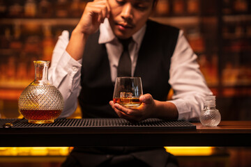 Business man bartender pours whiskey into a glass, sitting sadly in a restaurant