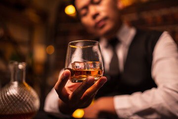 Business man bartender pours whiskey into a glass, sitting sadly in a restaurant