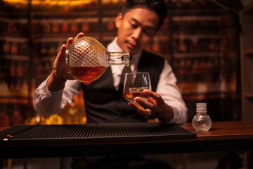 Business man bartender pours whiskey into a glass, sitting sadly in a restaurant