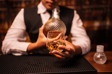 Business man bartender pours whiskey into a glass, sitting sadly in a restaurant