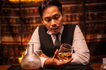 Business man bartender pours whiskey into a glass, sitting sadly in a restaurant	