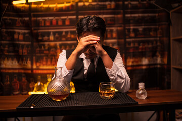 Business man bartender pours whiskey into a glass, sitting sadly in a restaurant.