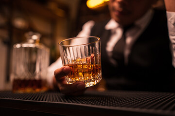 Business man bartender pours whiskey into a glass, sitting sadly in a restaurant.