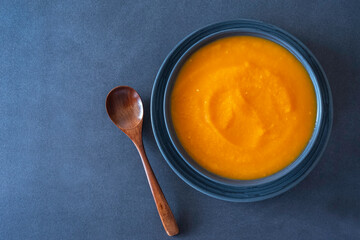 Bowl of pumpkin soup on dark background. Top view.
