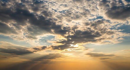 Dramatic sunset sky filled with varied clouds, showcasing sunbeams piercing through the atmospheric layers.