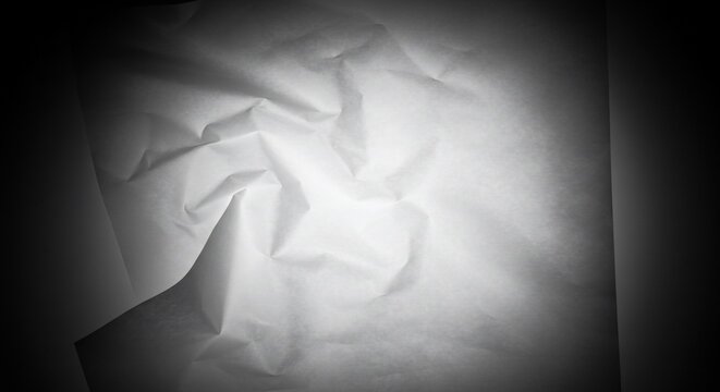 Abstract Crumpled White Paper Texture on Dark Background with Dramatic Lighting