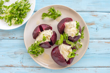 Beetroot filled with Georgian nut sauce on ceramic plate over blue wooden background.

