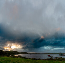 Obraz premium Dramatic sky over Loch Harport on the Isle of Skye, Scotland, with boats anchored near the shoreline under colourful evening clouds
