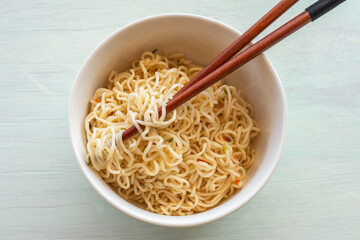 Instant noodles in ceramic bowl with chopsticks.
