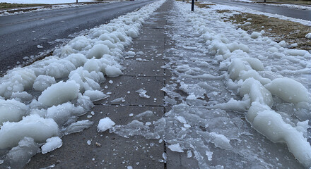 Frozen melted snow and ice on paved sidewalk in winter  
