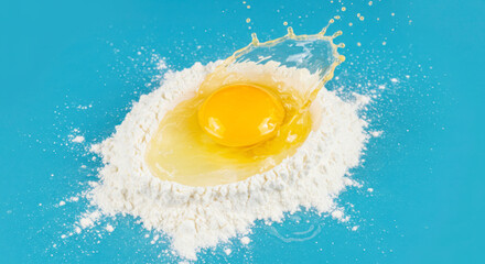 Bright Egg Yolk Splashing in Flour on Blue Background. World Egg Day Concept