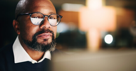 Fototapeta premium Computer, finance and night with business black man in office for portfolio or risk management. Face, glasses reflection and space with mature employee reading financial charts or graphs in evening