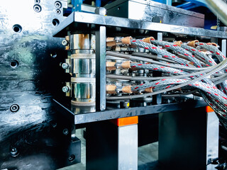 Close-up of metal mold components for injection and blow molding of bottles.