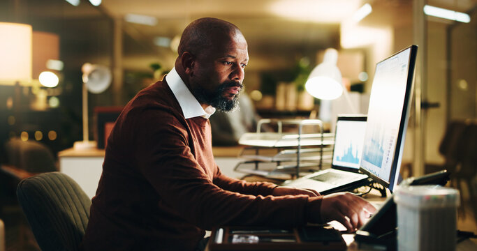 Computer screen, finance and tablet with business black man in office at night for investment. App, display and research with mature portfolio manager at work for evening review of charts or graphs - Powered by Adobe
