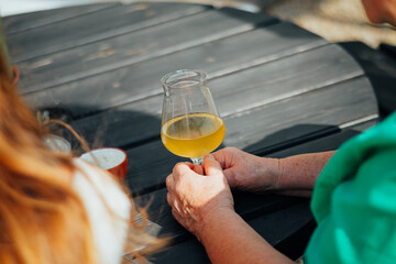 Hands Holding White Wine Glass Outdoors on Wooden Table