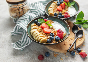 Healthy breakfast bowls with yogurt, granola, banana, and berries