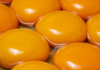 Close-up of several large yolks. The eggs are arranged in a way that creates a sense of depth and...