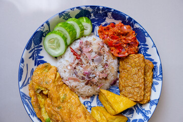 Homemade food torch ginger or kecombrang rice served with fried tofu and tempeh, sambal, omelette and cucumber
