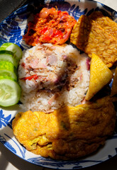 Homemade food torch ginger or kecombrang rice served with fried tofu and tempeh, sambal, omelette and cucumber