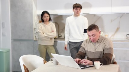 Couple young woman and young guy quarreling with adult man working on laptop in kitchen at home - Powered by Adobe