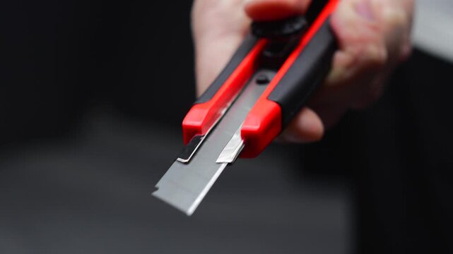 An office paper cutter with a sharp retractable blade.
A man holds a retractable office knife or cutter to cut paper and thin objects.