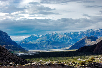Snow-Capped Mountains Overlooking a Valley with Cloudy Skies