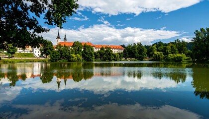 Fototapeta premium Tranquil lake reflecting a historic town under a summer sky