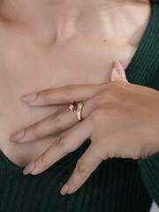 Close-up of a woman’s hands wearing a unique gold ring with a red gemstone and artistic design, showcasing elegance and modern jewelry style.
