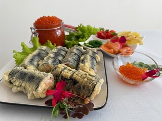 fried rolls in batter decorated sushi on a plate. Sushi is the traditional Asian and Japanese food. Roll of sushi prepared from raw fish and a special rice. Diet healthy food.
