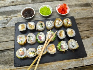 An assortment of typical Japanese dishes on a granite board next to various sauces