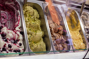 A close-up shot of three tubs of gourmet gelato, showing vibrant swirls of strawberry, creamy white, and deep raspberry flavors, ideal for food and beverage marketing or menu design