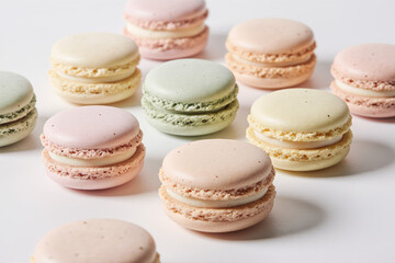 Obraz premium Photograph of pastel-colored macarons in pink, green, and beige, arranged on a white surface. Macarons have smooth tops and textured edges. 