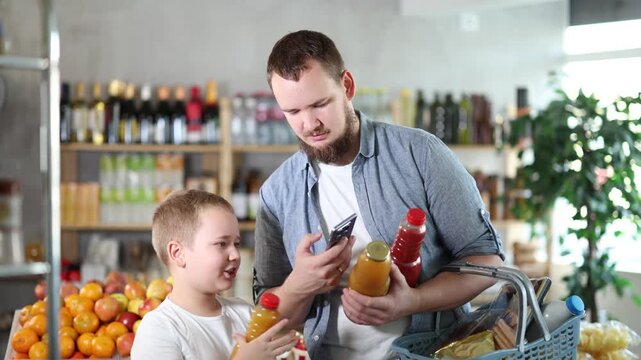 European man with son customer at shop scan QR code on juice bottle using phone camera. Client study composition, manufacturer information of product using application. Visitor examines product