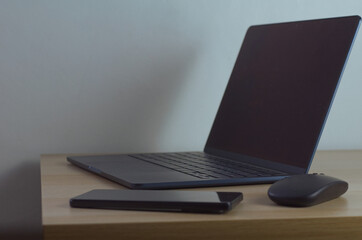 Modern Workspace with Laptop, Smartphone, and Mouse on Wooden Desk