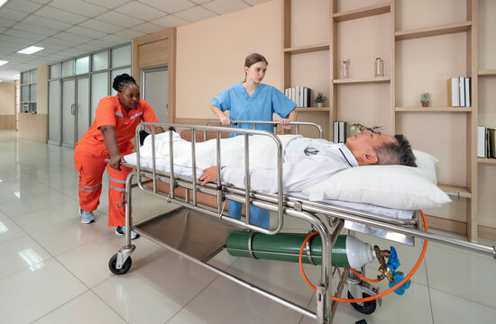 Two healthcare worker are hurriedly transferring a patient on a stretcher in a  well-lit hospital hallway during the day, illustrating urgency and teamwork in medical care. - Powered by Adobe