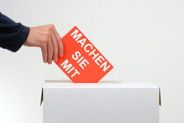 Machen Sie mit - Hand wirft Stimmzettel in Wahlurne