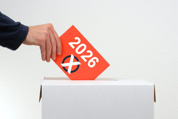Wahl im Jahr 2026 - Hand wirft Stimmzettel in Wahlurne