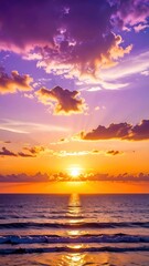 Vivid vertical view of ocean at sunset with striking orange and purple hues across the sky and water reflecting the sun
