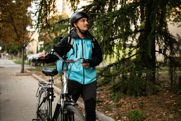 Deliveryman walking with his bicycle and holding a smartphone