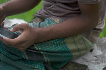 Man sitting outdoors holding a smartphone in his hands