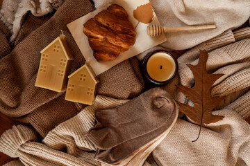 Cozy autumn still life with candles, croissant, and warm socks.