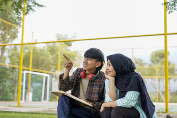 Two Diverse Young Adults Engaging in Conversation Outdoors A Moment of Shared Observation and Discovery, Pointing and Smiling, Enjoying Leisure Time, in a Park Setting