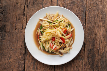 Spicy Thai Papaya Salad with Crispy fish on Wooden Table