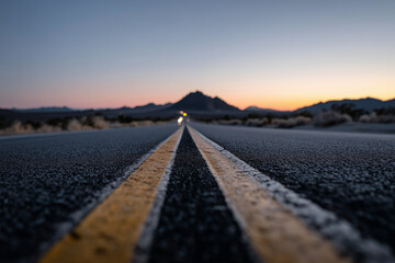 Deserted road vanishing into dark twilight, faint glow of headlights,