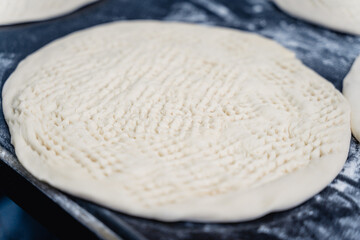 Dough for Uzbek flatbread is rolled out on table
