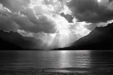 Black and white landscape view of a lake, mountains, and dramatic clouds with sun rays
