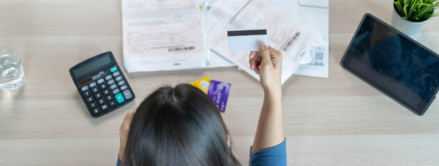 Top view of stressed young asian woman trying to find money to pay credit card debt. Selective focus on hand.