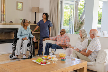 Senior friends enjoying conversation with caregiver in cozy living room setting